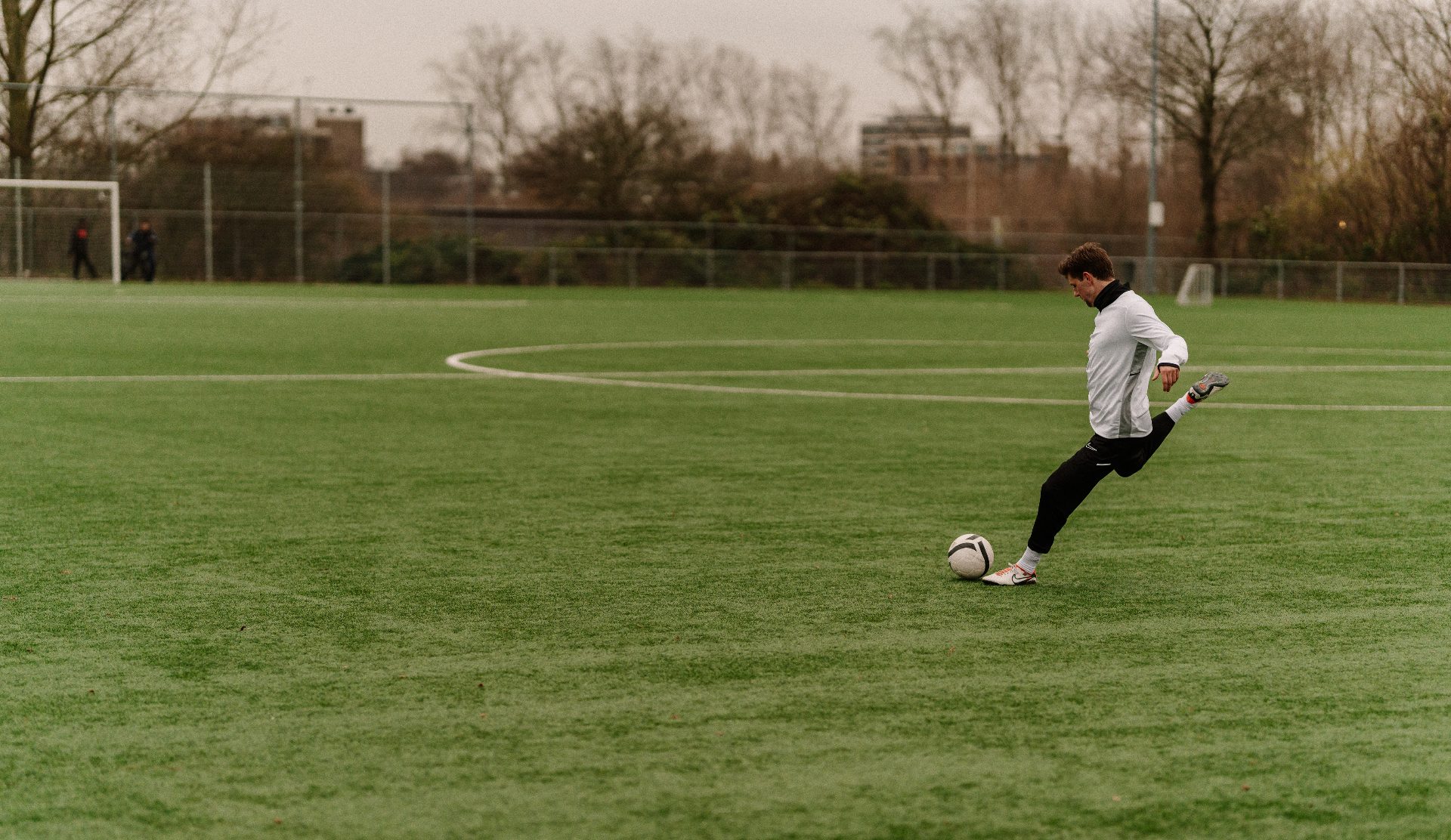 Voetballer haalt uit op een kunstgrasveld